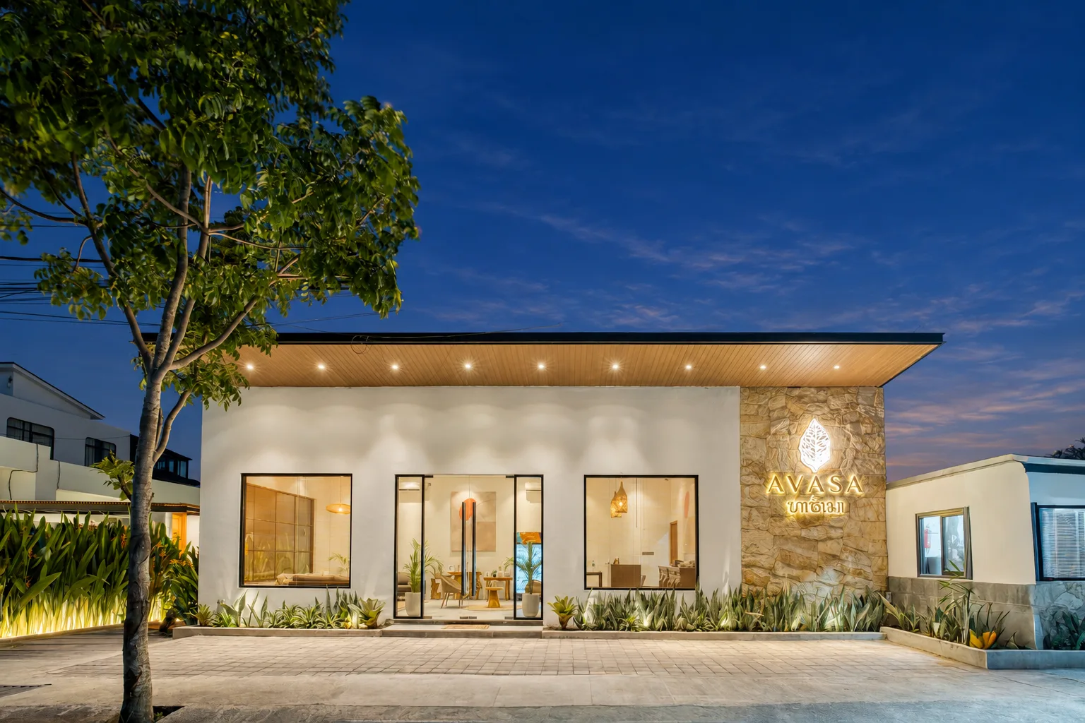 The AVASA lobby at dusk, with a lit entrance and AVASA sign on its stone facade.