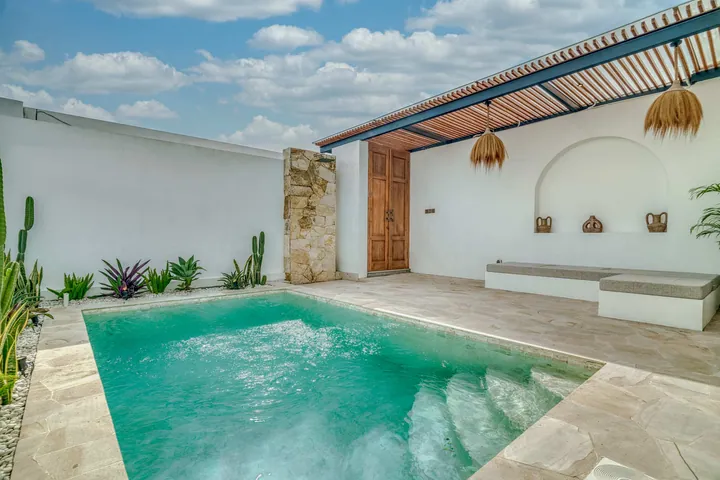 Poolside terrace with a built-in bench, loungers, stone paving and a timber pergola.