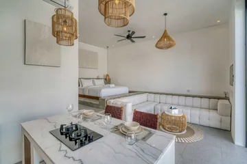 Kitchen island with cooktop and place settings in front of the sectional sofa and bed.