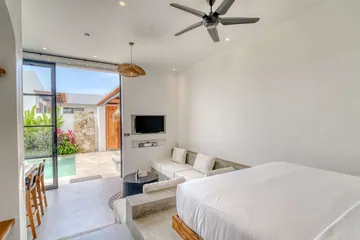 View from the bed toward a wall-mounted television and glass doors open to the pool.