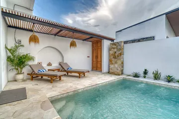 A courtyard pool facing a shaded terrace with two timber loungers.