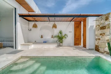 Turquoise pool surrounded by pale paving and white courtyard walls.