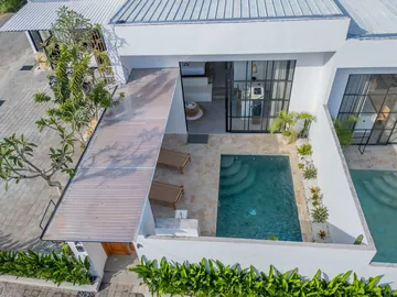 Aerial view into a courtyard pool with stepped entry beside a covered walkway and planting.