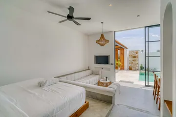 Bedroom and lounge with white bed, sectional and glass doors to the patio.
