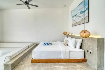 White bed on a low wood platform beneath a small landscape artwork.