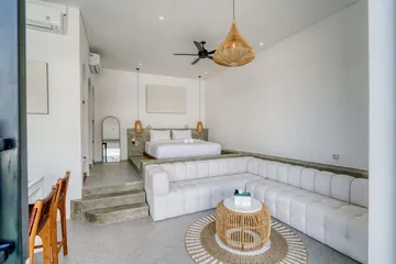 Wide view across a white bed and sectional toward glass doors and courtyard.