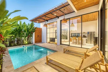 Poolside loungers beneath a timber canopy beside glass doors.
