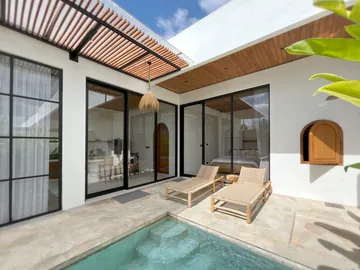 Courtyard pool with two loungers in front of black-framed glass doors and an arched timber window.