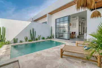 Courtyard pool beside a glass-fronted villa and paved terrace.