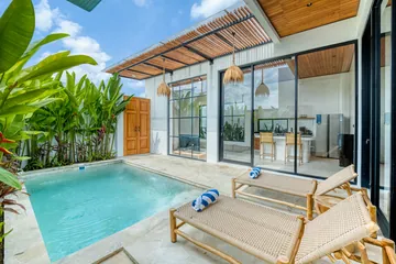 Pale paved terrace with turquoise pool and two wooden loungers.