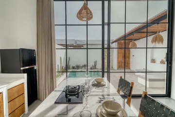 Kitchen island with place settings and cooktop beside black-framed glass doors.