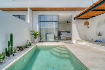 Small courtyard pool viewed from the terrace between white walls.