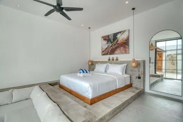 Low bed and sectional sofa in a bright room with a ceiling fan and framed artwork.