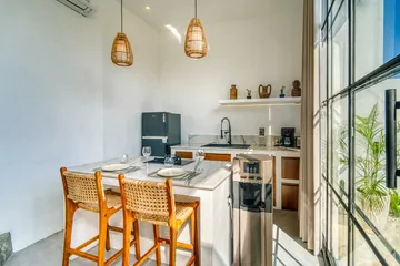 A light-filled living or kitchen space with pale finishes and timber furniture.