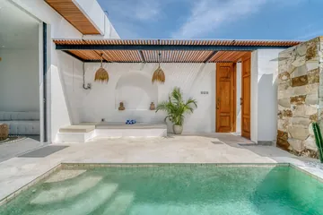 Turquoise pool and pale paved terrace beside the villa's glass doors.