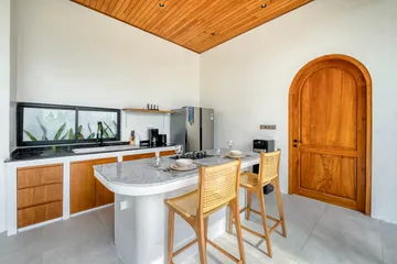 Kitchen counter and cooktop beside a wood door and long horizontal window.