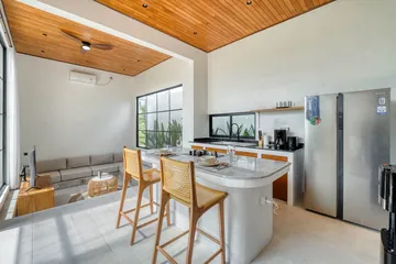 Kitchen island with two stools beside glass doors and courtyard greenery.