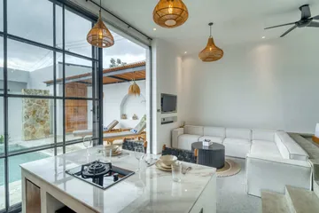 Kitchen island with place settings beside large glazing and pale stone counters.