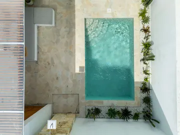 Top-down view of a long, narrow courtyard pool beside a stone deck and a strip of planting.