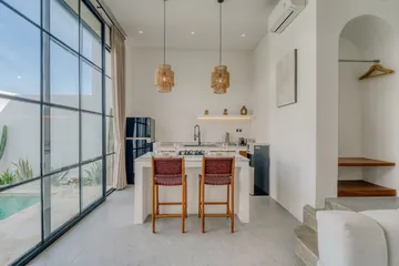 Kitchen counter and dining stools beside a floor-to-ceiling glass wall.