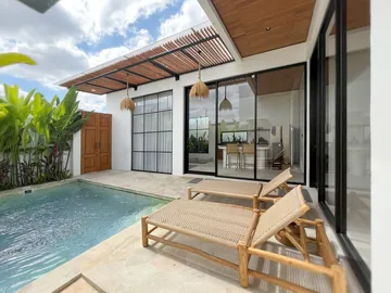 Daytime courtyard with turquoise pool, pale paving and glass-fronted room.