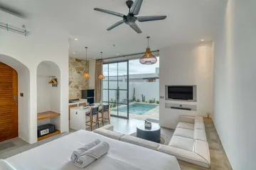 View across a sectional toward the courtyard through tall glass doors, with a wall-mounted television.