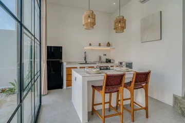Kitchen counter and stools beside floor-to-ceiling glazing and dining area.