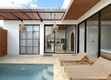 Bright courtyard pool surrounded by pale stone paving and white walls.