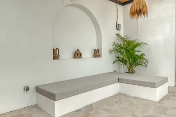Built-in stone bench curves around a paved courtyard beneath an arched wall niche.