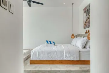 Low bed beside glass doors, with a raised stone platform and a small round bedside table.