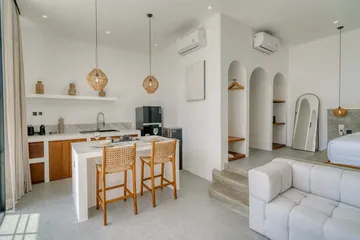 Kitchen and lounge with white sectional, dining counter and glass doors.