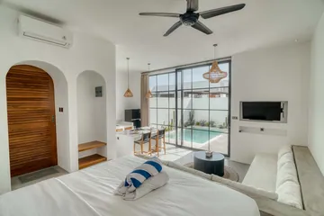 View from the bed toward an arched timber door, a wall-mounted television and glass doors to the pool.