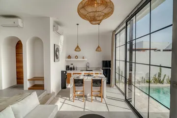Dining island and kitchen shelving between arched doorways and a full-height glass wall.