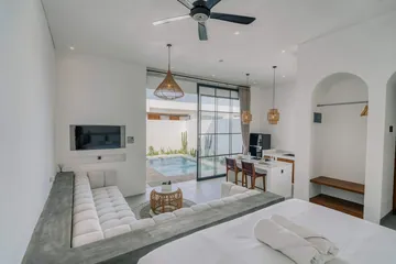 Open room with a white bed and sectional facing full-height glass doors.