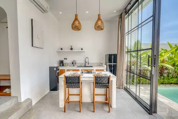 Dining island and kitchen beside full-height glass doors opening to the pool.