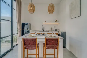 A light-filled living or kitchen space with pale finishes and timber furniture.