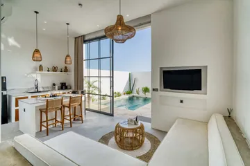 Open room with white sofa, wall television, dining counter and glass doors.