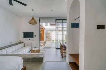 White bed and lounge seating beside glass doors opening to the patio.