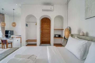 Bedroom with white bedding and wood-framed bed beside open patio doors.