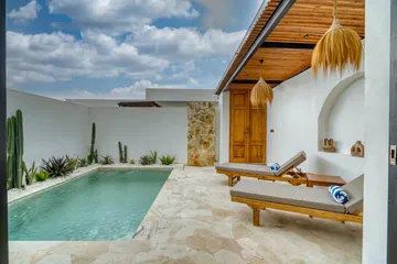 Poolside view of two loungers beneath a timber pergola, with white walls and stone accents.