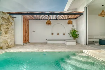 Courtyard pool framed by pale walls, timber roof slats and green planting.