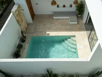 Top-down courtyard view showing a rectangular pool, stone paving and planted border.