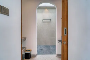 Small bathroom with an arched shower opening and pale stone interior.