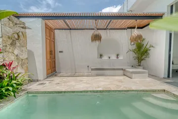 A courtyard pool facing a built-in bench, an arched wall niche and a timber door.