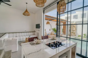 Open-plan room with bed, sectional, wall television and glass doors to courtyard.