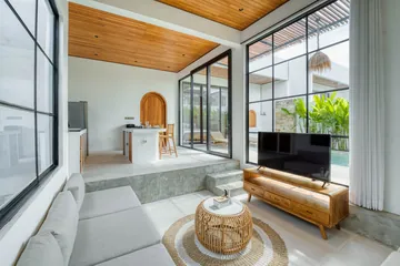 Living room with white sectional, low wood table and garden-facing window.