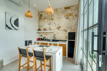 Stone-backed kitchen and dining table by glass doors, with a framed abstract print on the wall.