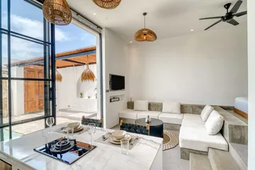 Open-plan room with a kitchen island in front, and a sectional and low bed beyond.