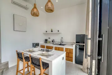Kitchen island with dining chairs and a pale stone backsplash beside tall glass doors.