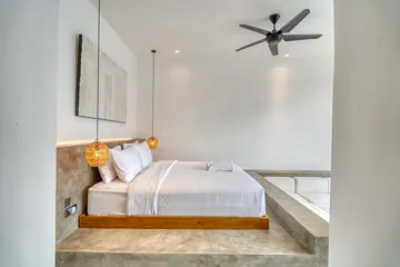 White bedding on a timber bed beside a pale wall and an arched mirror.